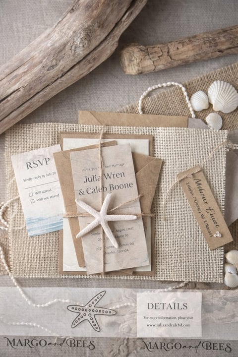 Beach-themed wedding invitation suite with starfish, seashells, driftwood, and kraft paper elements on a woven beige backdrop